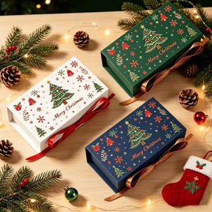 Könnte beinhalten: Drei rechteckige Geschenkboxen in Weiß, Dunkelgrün und Marineblau, jeweils mit einem Muster aus Weihnachtsbäumen, Glocken und Schneeflocken sowie dem Schriftzug Merry Christmas. Jede Box verfügt über einen Satinbandverschluss und einen Magnetdeckel.