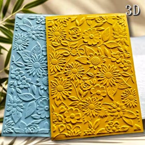 Puede incluir: Dos carpetas de relieve 3D rectangulares con diseños florales. Una es azul claro, la otra amarilla. Los diseños incluyen girasoles, rosas y hojas. Para proyectos de manualidades o scrapbooking.