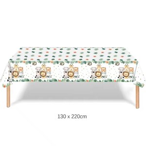 Puede incluir: Mantel rectangular blanco con un patr&oacute;n repetido de animales de safari de dibujos animados, hojas verdes y flores naranjas. El mantel mide 130 x 220 cm y est&aacute; sobre una mesa de madera.