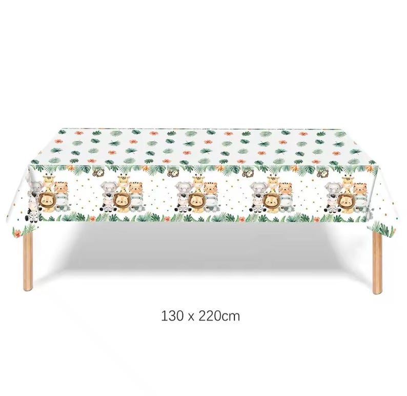 Puede incluir: Mantel rectangular blanco con un patr&oacute;n repetido de animales de safari de dibujos animados, hojas verdes y flores naranjas. El mantel mide 130 x 220 cm y est&aacute; sobre una mesa de madera.