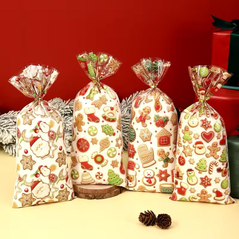 Puede incluir: Cuatro bolsas de regalo festivas llenas de golosinas, con una variedad de galletas de jengibre con tem&aacute;tica navide&ntilde;a. Las bolsas son blancas con ilustraciones coloridas de Pap&aacute; Noel, hombres de jengibre y &aacute;rboles de Navidad. Cada bolsa est&aacute; atada con un lazo dorado.