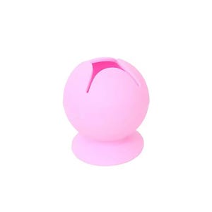 Puede incluir: Objeto esférico rosa claro con un diseño en forma de flor en la parte superior. El objeto tiene una base redonda y un centro hueco. La parte superior tiene cuatro aberturas en forma de pétalo, revelando un interior rosa más oscuro. El objeto es de material blando.