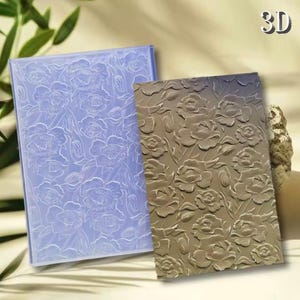 May include: A rectangular light purple silicone embossing mat and a matching rectangular brown embossed panel, both featuring a repeating floral pattern of roses and leaves. The text 3D is visible in the upper right corner of the image.