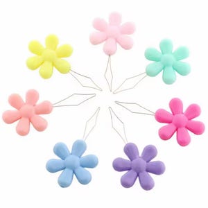 Puede incluir: Un conjunto de enhebradores con forma de flor en colores amarillo, rosa, azul, morado y verde. Cada enhebrador tiene un pequeño lazo de alambre, diseñado para facilitar el enhebrado de agujas. Ideales para costura y manualidades.