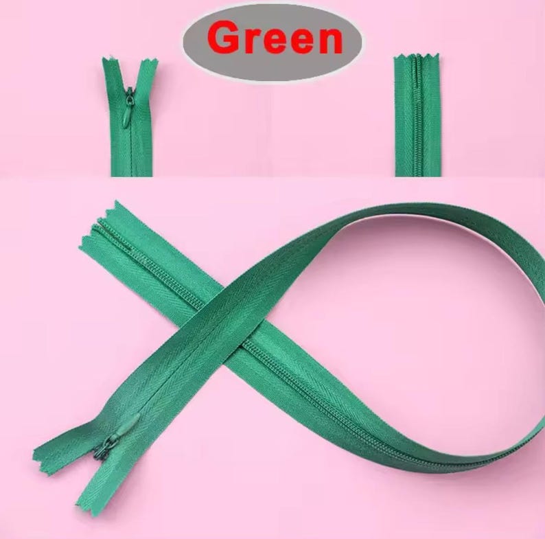 Puede incluir: Cremalleras verdes sobre un fondo rosa. La palabra "Green" est&aacute; en un &oacute;valo rojo en la parte superior. Una cremallera est&aacute; abierta, otra cerrada y otra curvada. Estas cremalleras son para coser y manualidades.