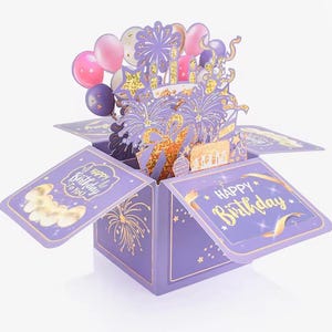 May include: A purple pop-up birthday card with gold detailing. The card, in a box, features a cake, fireworks, and balloons. The box has the words "Happy Birthday" and "Happy Birthday to You" in gold lettering.