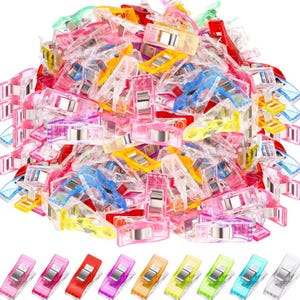 May include: A collection of multi-coloured sewing clips in shades of pink, red, yellow, blue, green, and clear. The plastic clips have a metal hinge. A row of clips in different colours is at the bottom of the image.