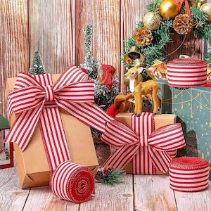 Könnte beinhalten: Rot-weiß gestreifte Bänder und Schleifen schmücken verpackte Geschenke und schaffen eine festliche Urlaubsszene. Rollen mit Bändern und dekorativen Elementen sind auf einer Holzoberfläche angeordnet.