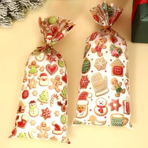 Puede incluir: Dos bolsas de regalo transparentes de celof&aacute;n llenas de galletas navide&ntilde;as. Las bolsas est&aacute;n decoradas con varias galletas de jengibre, Pap&aacute; Noel y dise&ntilde;os de &aacute;rboles de Navidad. Las bolsas est&aacute;n atadas en la parte superior con lazos dorados.