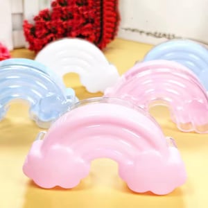 Peut inclure: Plusieurs objets en forme d'arc-en-ciel aux couleurs pastel. Les arcs-en-ciel sont dans des tons de rose, de bleu et de blanc, avec un design en forme de nuage aux extrémités. Ils sont disposés sur une surface jaune, suggérant un thème décoratif ou ludique.