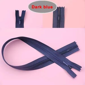 Puede incluir: Cremalleras azul oscuro en varias etapas de cierre sobre un fondo rosa. El texto "Dark blue" est&aacute; en un &oacute;valo gris. Una cremallera est&aacute; completamente cerrada, otra parcialmente.