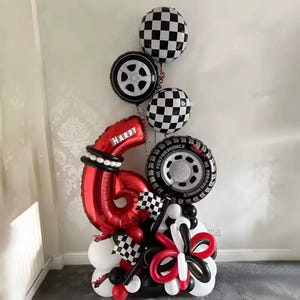 Könnte beinhalten: Eine festliche Ballon-Arrangement mit einer großen roten Zahl sechs, dem Namen "Harry", und Rennsport-Elementen. Die Anordnung umfasst karierte und reifenförmige Ballons sowie schwarz-weiße Akzente, ideal für einen Geburtstag.