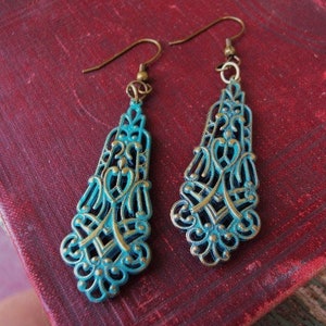 May include: A pair of turquoise and gold filigree dangle earrings. The earrings have a delicate, intricate design and are perfect for adding a touch of elegance to any outfit.