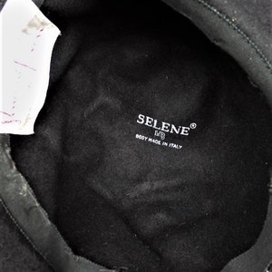 May include: Black felt beret with a black fabric lining. The lining has a white label with the text "SELENE&reg; BODY MADE IN ITALY".