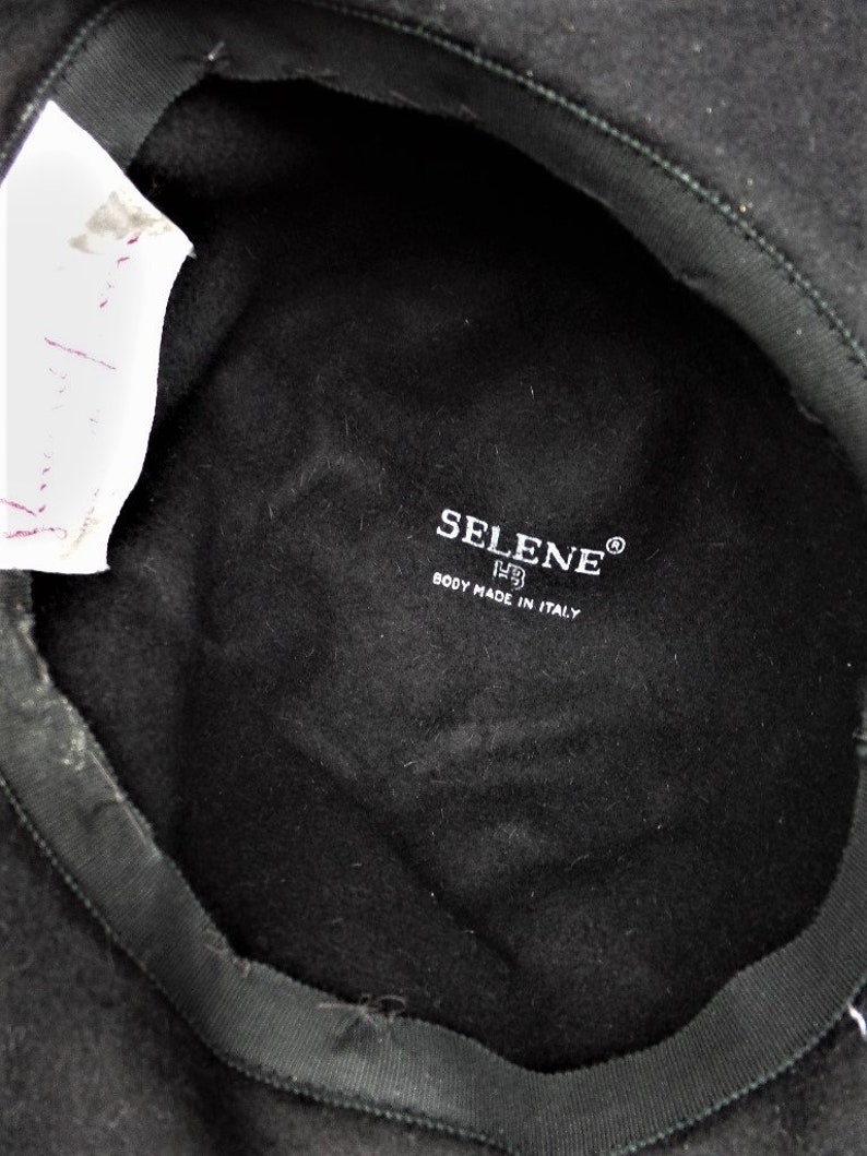 May include: Black felt beret with a black fabric lining. The lining has a white label with the text "SELENE&reg; BODY MADE IN ITALY".