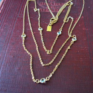 May include: A gold chain necklace with multiple strands and small clear stones. The necklace is layered and has a delicate look.
