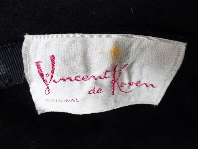 May include: A white label with pink embroidery that reads "Vincent de Koven ORIGINAL".