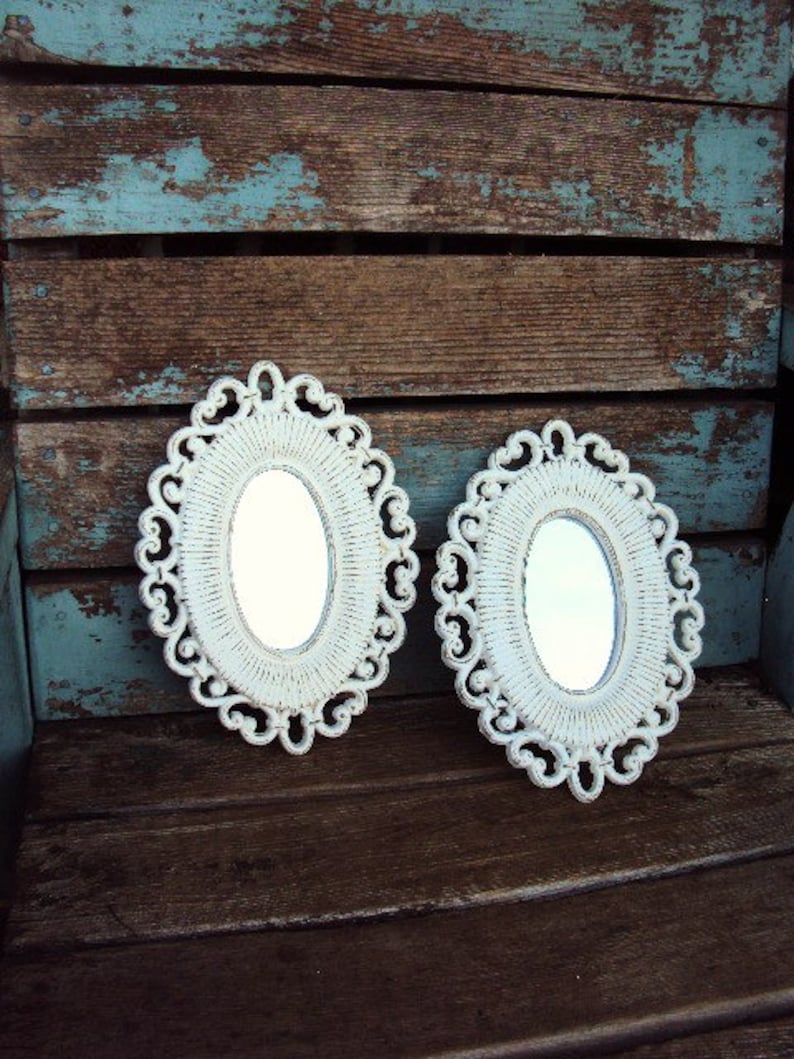 May include: Two white oval mirrors with ornate frames, set against a rustic wooden background with blue paint.