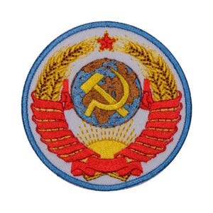 May include: A round embroidered patch with a red star, a globe with a hammer and sickle, and wheat stalks. The patch is surrounded by a blue border.