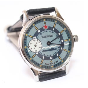 At nine o'clock there is an additional dial for the second hand. At the top at 12 o'clock there is a star with the inscription "Captain's" under it. At the bottom of the dial there is an image of a submarine.