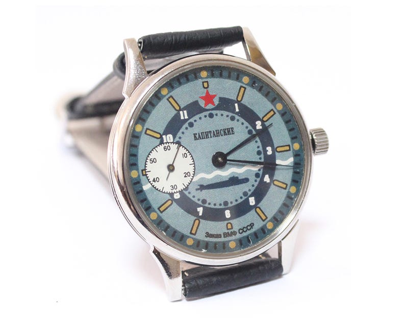 At nine o'clock there is an additional dial for the second hand. At the top at 12 o'clock there is a star with the inscription "Captain's" under it. At the bottom of the dial there is an image of a submarine.