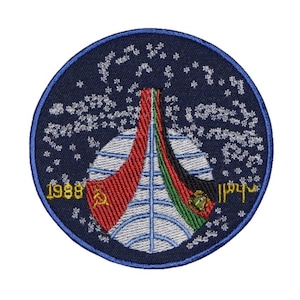Op de afbeelding: Een blauwe geborduurde patch met een witte wereld, rode en groene strepen en de tekst "1988" en "1111".