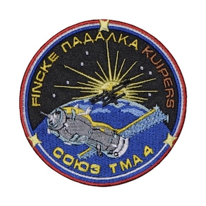 Puede incluir: Un parche redondo bordado con un borde azul, blanco y rojo. El centro del parche presenta un fondo negro con un sol amarillo y una nave espacial en órbita alrededor de una Tierra azul y blanca. El texto "FINCKE PADALKA KUI PERS" está escrito en amarillo alrededor del borde del parche. El texto "СОЮЗ ТМА 4" está escrito en blanco en la parte inferior del parche.