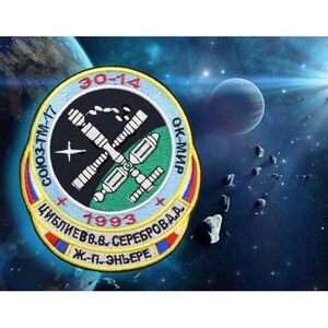 May include: A circular embroidered patch with a black background and a white outline. The patch features a space station with a green and white color scheme. The text "СОЮЗ-ТМ-17 30-14 ОК-МИР 1993 ЦИБЛИЕВ В.В. СЕРЕБРОВА А.А. Ж.-П. ЭНЬЕРЕ" is embroidered in white and yellow around the space station.