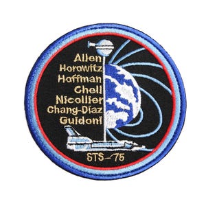 Puede incluir: Parche bordado con un globo terráqueo azul y blanco, una nave espacial y los nombres Allen, Horowitz, Hoffman, Chell, Nicollier, Chang-Diaz y Guidoni. El parche tiene un borde azul y rojo y el texto "STS-75".
