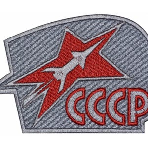 May include: A red star with a white rocket inside, with the text "CCCP" below. The star and text are embroidered on a gray fabric background.