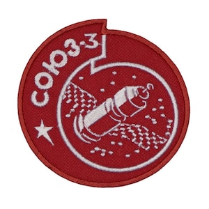 May include: Red embroidered patch with white lettering that says "Союз 33" and a white illustration of a rocket in space.
