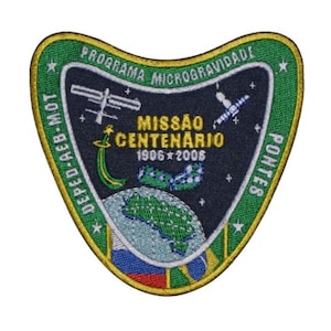 Puede incluir: Un parche bordado verde, amarillo y azul con el texto "Programa Microgravidade Deped-Mob-Mot Pontes" y "Missão Centenario 1906 * 2006". El parche presenta una imagen estilizada de la Tierra, un transbordador espacial y un satélite.