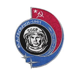 May include: Embroidered patch featuring a portrait of a cosmonaut in a helmet, with the text "Ю.А.ГАГАРИН - 1961 CCCP". The patch has a red and blue color scheme with a star and hammer and sickle symbol.