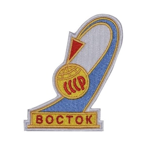 May include: A white, blue and yellow embroidered patch featuring a red arrow and a globe with the letters "CCCP" inside. The text "BOCTCK" is written in yellow on a white banner at the bottom of the patch.
