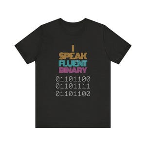 May include: A black t-shirt featuring the text "I Speak Fluent Binary" in a colourful, retro-style font. The text is followed by three lines of binary code: "01101100", "01101111", and "01101100".