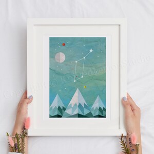 May include: A framed print of a constellation with a white moon and stars on a blue and green watercolour background with geometric mountains at the bottom.