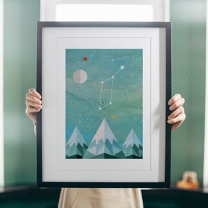 May include: A framed print depicting a constellation with a geometric mountain range in the foreground. The sky is a blue-green watercolour wash with white stars and a crescent moon. The mountains are a mix of blue and green with white snow peaks.