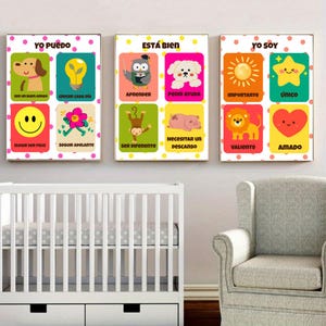 Könnte beinhalten: Drei gerahmte Kunstdrucke mit farbenfrohen Illustrationen und spanischem Text. Jeder Druck zeigt sechs Bilder mit positiven Affirmationen und niedlichen Tierfiguren. Die Drucke werden über einem weißen Kinderbett und einem grauen Sessel angezeigt.