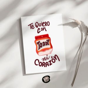 Könnte beinhalten: Eine weiße Karte mit den Worten "Te Quiero con mi Corazón" in burgunderfarbener Schrift. In der Mitte befindet sich eine rot-weiße Illustration eines Toddy-Glases. Das Logo des Künstlers befindet sich in der unteren Ecke.