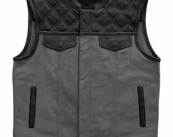 May include: A black and gray vest with a quilted black leather upper section and two front pockets. The lower section is gray with two vertical pockets and a black leather trim along the bottom.