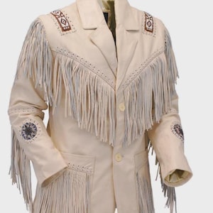 Puede incluir: Chaqueta de cuero color crema con flecos en el pecho, las mangas y los bolsillos. La chaqueta presenta bordados decorativos en los hombros y las mangas, y tiene una botonadura frontal. Un diseño clásico de inspiración occidental.