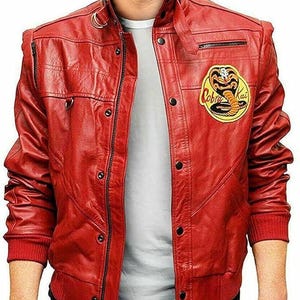 Puede incluir: Chaqueta de cuero roja con cremallera negra y cierres de botón a presión. La chaqueta presenta un parche de Cobra Kai en el pecho. Tiene cuello alto y dobladillo y puños de canalé.