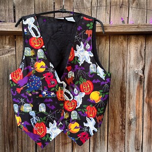 Vintage 90s Basic Editions Halloween Vest - Spooky Grannycore Print M/L A 90s vintage Basic Editions Halloween vest, featuring a playful all-over print with ghosts, pumpkins, skeletons, witches, and gravestones on a black background