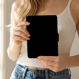 May include: A solid black rectangular tablet or e-reader case with rounded corners and a small side tab, held upright in a vertical orientation. The object features a smooth, matte finish and a simple, clean design without any visible branding or markings.