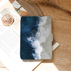 Könnte beinhalten: Eine rechteckige Hülle mit einem Design aus blauen und weißen Meereswellen. Die Hülle ist geöffnet und gibt einen Einblick in das Innere. Das Design zeigt dunkelblaues Wasser und weiße, schäumende Wellen.