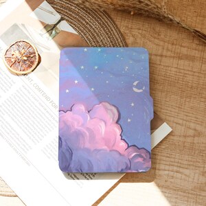 May include: A rectangular case with a painted night sky design. The artwork features a large pink and purple cloud, a crescent moon, and white stars against a blue background. The case is resting on a wooden surface.