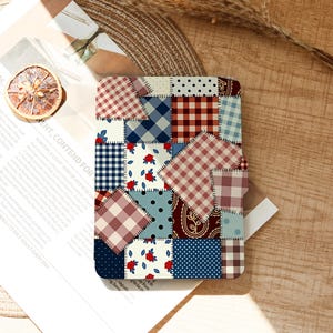 Könnte beinhalten: Eine rechteckige E-Reader-Hülle mit einem Patchwork-Design aus verschiedenen Stoffmustern, darunter rot-weißes Vichy-Karo, blau-weißes Schottenkaro, cremefarbene Stoffe mit roten Blumenmustern und dunkelblaue Stoffe mit weißen Punkten, verbunden durch Nähte.