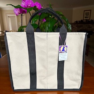 May include: A natural canvas tote bag with black straps.