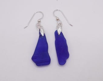 May include: A pair of earrings featuring blue sea glass with silver hooks.