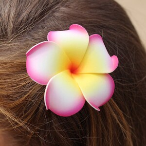 Pu&ograve; includere: Un fermaglio per capelli a forma di fiore rosa e giallo con un centro bianco. Il fiore &egrave; fatto di tessuto e ha un aspetto realistico.